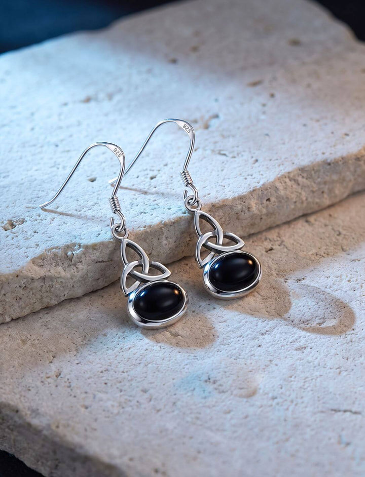 Trinity Knot Ohrringe aus Silber mit schwarzem Onyx auf hellem Kalkstein