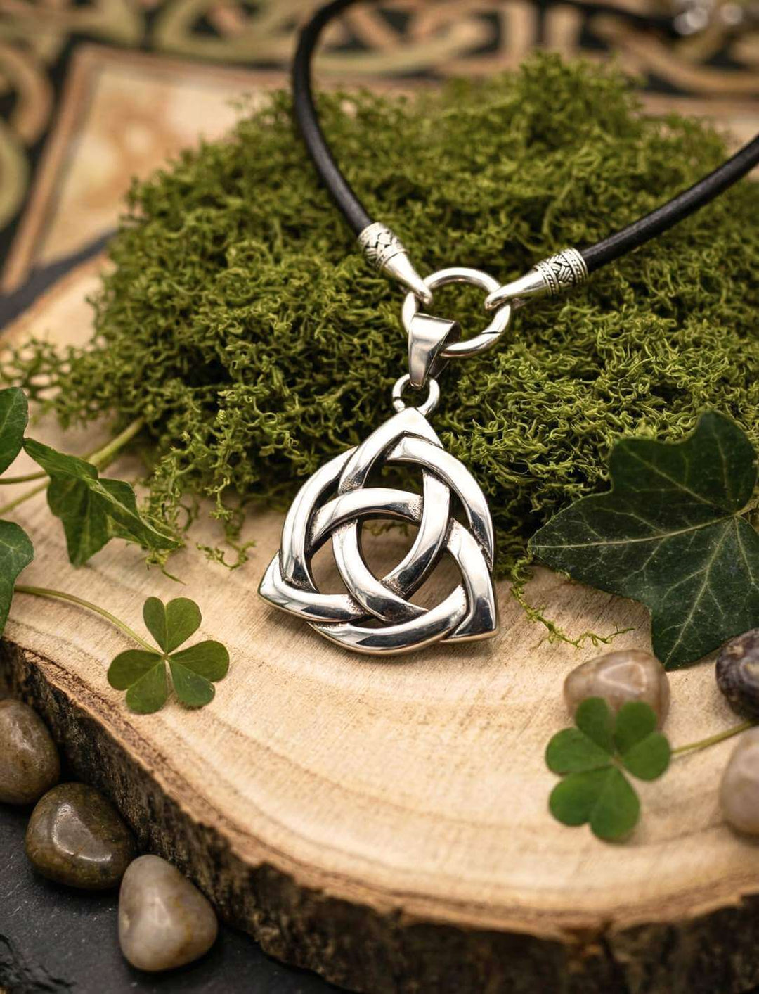 Triquetra keltischer Knoten Anhänger Edelstahl auf Holz mit Moos und Kleeblatt mit Lederkette in schwarz.
