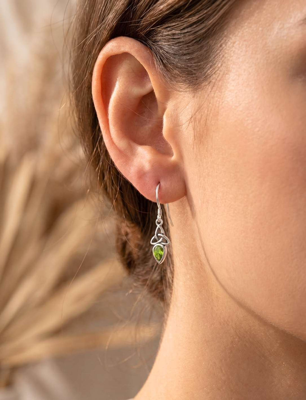 Triquetra Ohrhänger mit Peridot am Ohr getragen