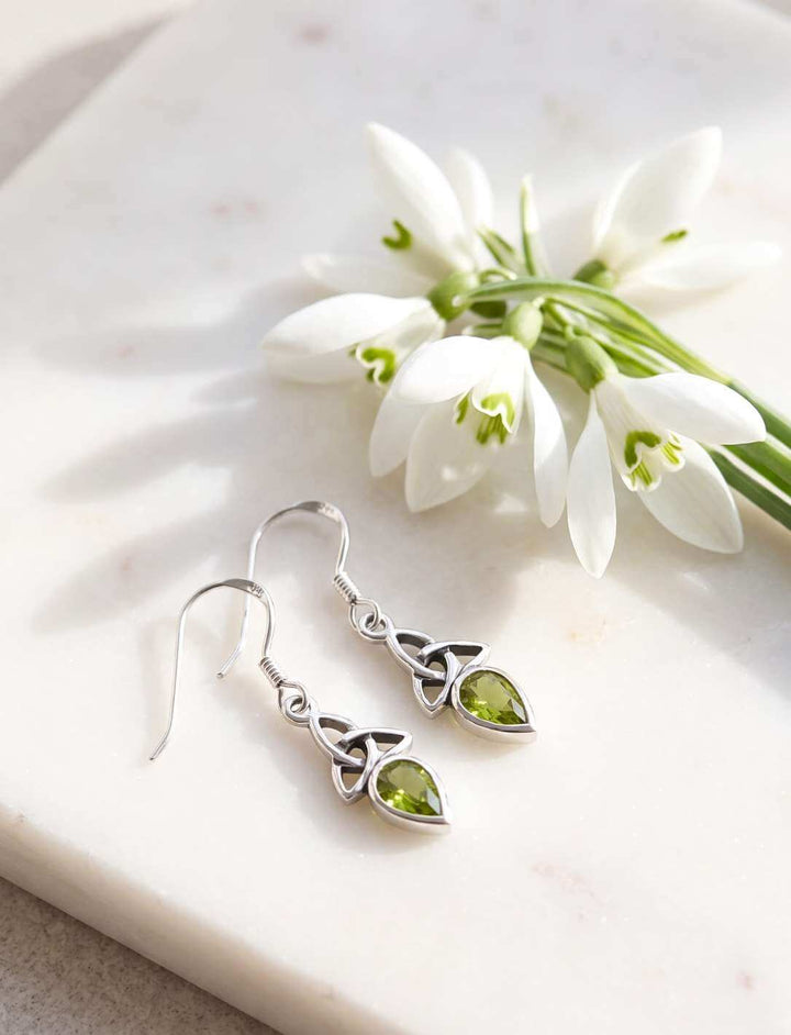 Triquetra Ohrhänger Silber mit Peridot neben Schneeglöckchen