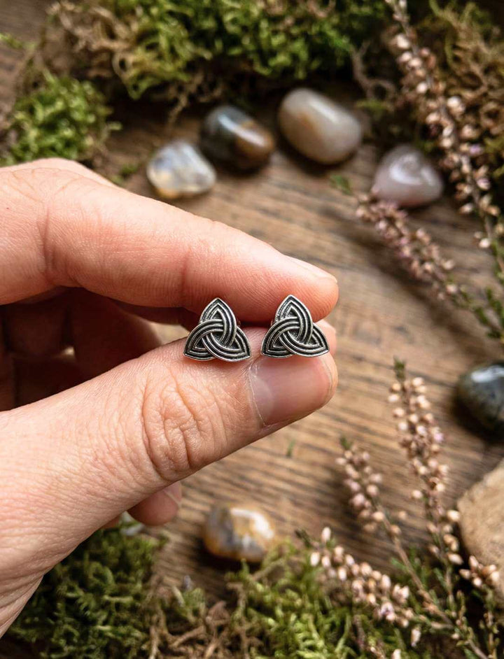 Hand hält Triquetra Ohrstecker aus 925 Silber zwischen Heidekraut und Moos