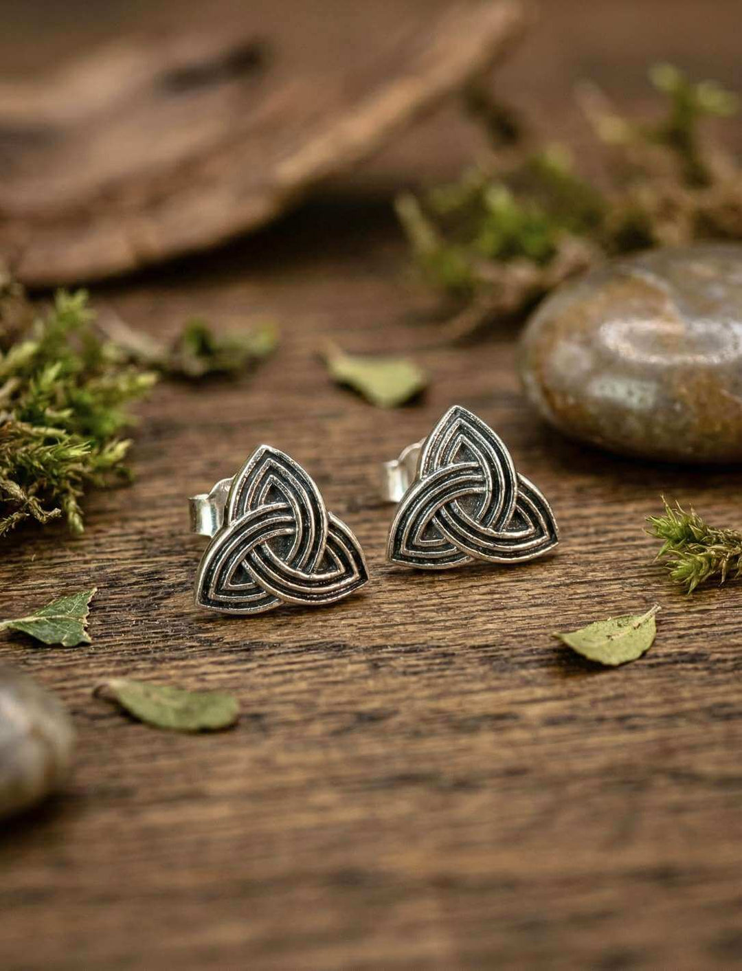 Triquetra Ohrstecker Paar auf Holztisch mit Moos und Blättern