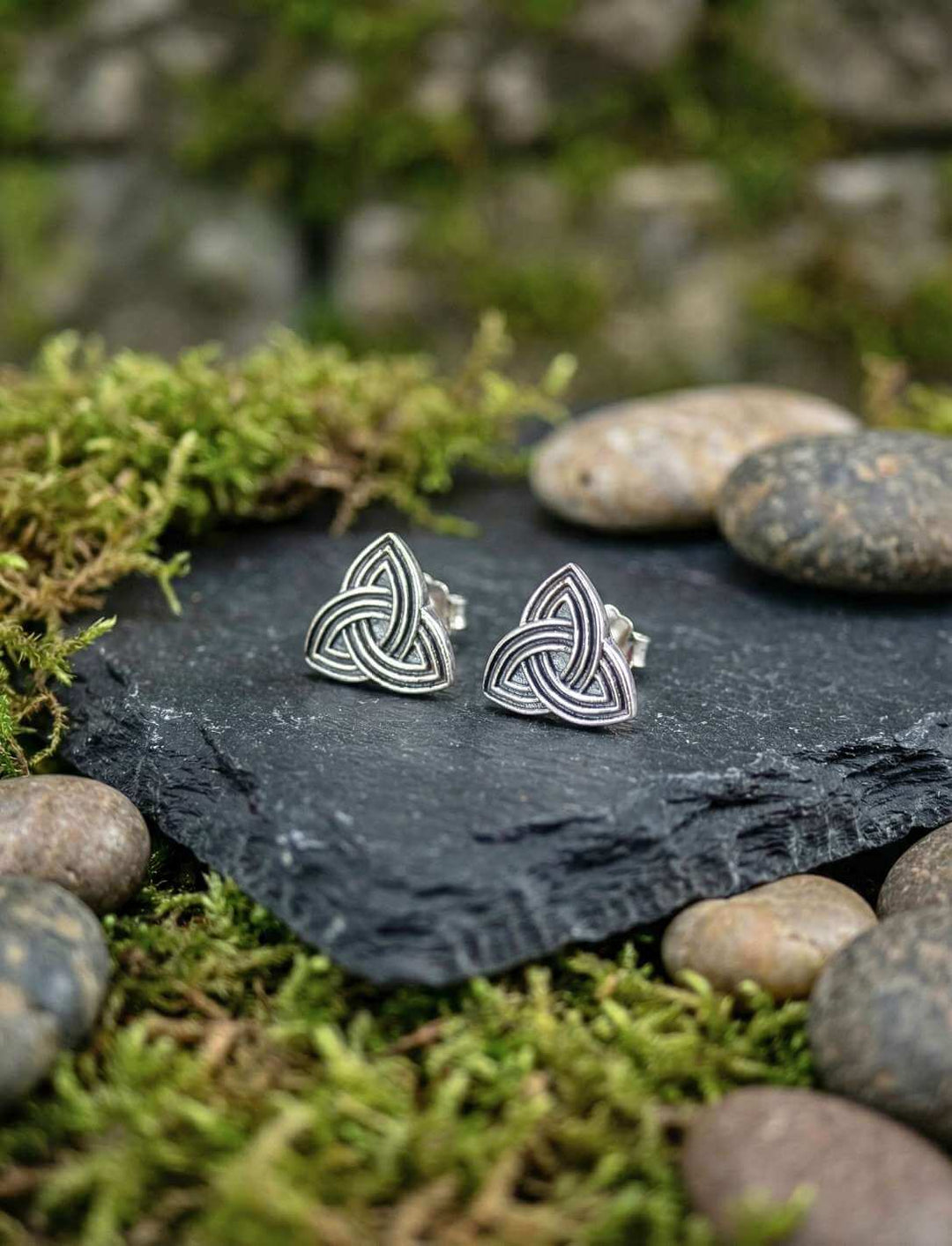 Keltische Triquetra Ohrstecker auf dunklem Schiefer mit Steinen