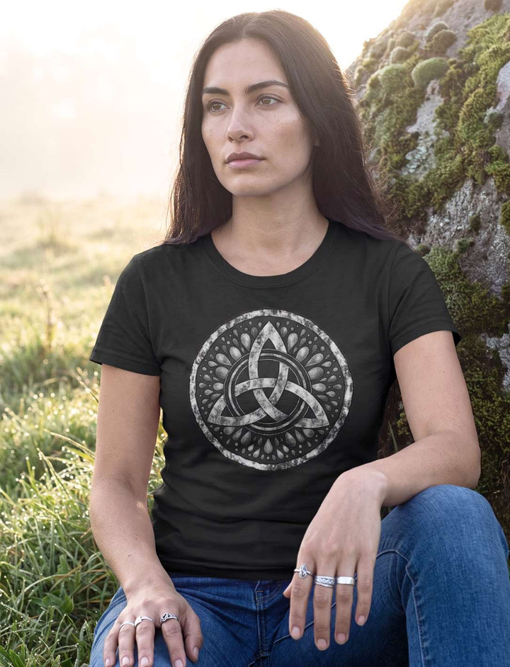 Frau sitzt im schwarzen Damen T-Shirt mit Triquetra auf einem Felsen auf der Morgenwiese