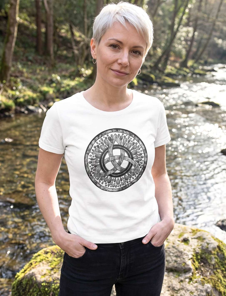 Frau mit platinblondem Kurzhaarschnitt im weissen Damen Shirt mit Triquetra am Waldbach