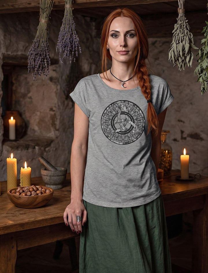 Graumeliertes Damen Longshirt mit Triquetra, Frau steht in einer Kräuterstube mit Kerzen und getrockneten Kräutern