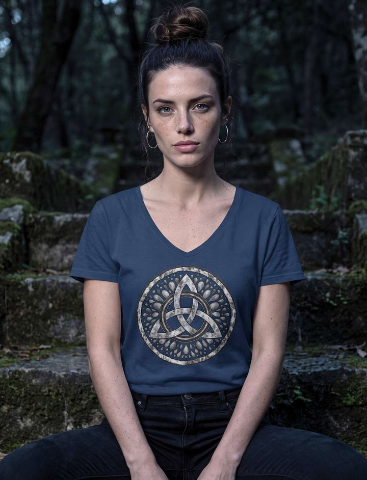 Navy V-Neck Shirt mit Triquetra, Trägerin sitzt auf moosigen Steinstufen im dunklen Wald