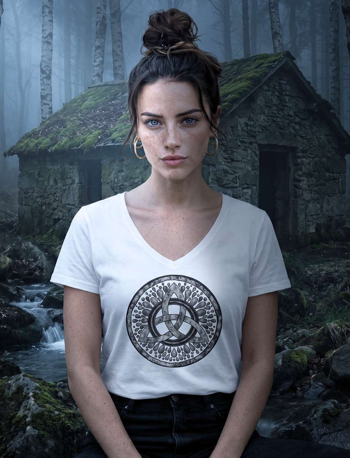 Weisses V-Neck Shirt mit keltischem Motiv, Trägerin sitzt an einer moosigen Steinhütte in der Blauen Stunde