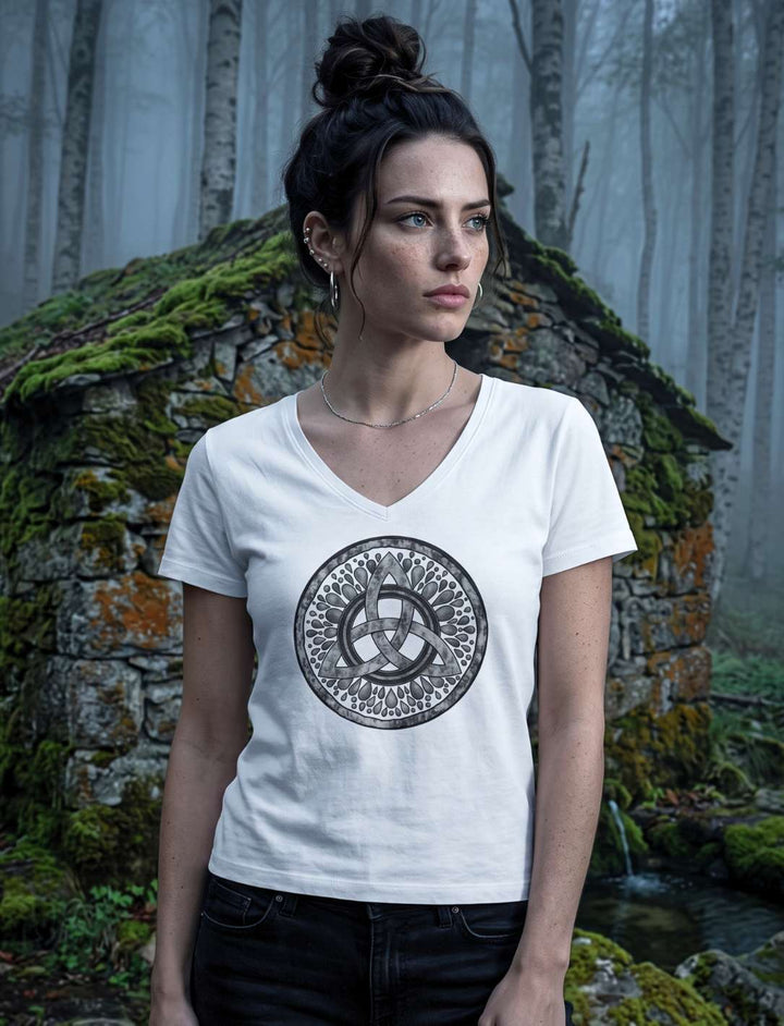 Frau im weissen Damen V-Neck Shirt mit Triquetra vor einer verlassenen Steinhütte im Birkenwald