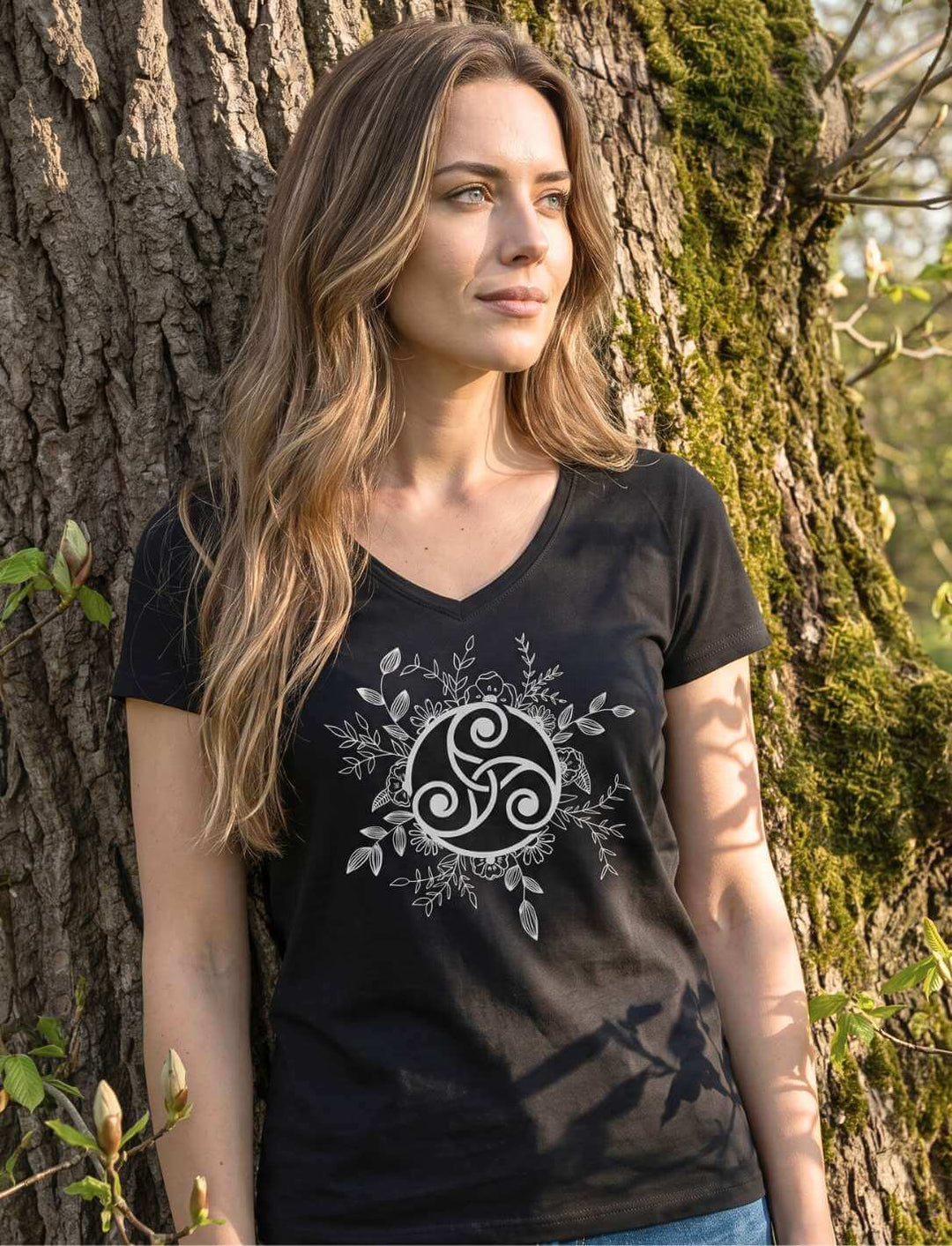 Triskele der ewigen Wandlung - Keltisches Damen V-Neck Shirt in Schwarz, getragen an einem alten moosbewachsenen Baumstamm