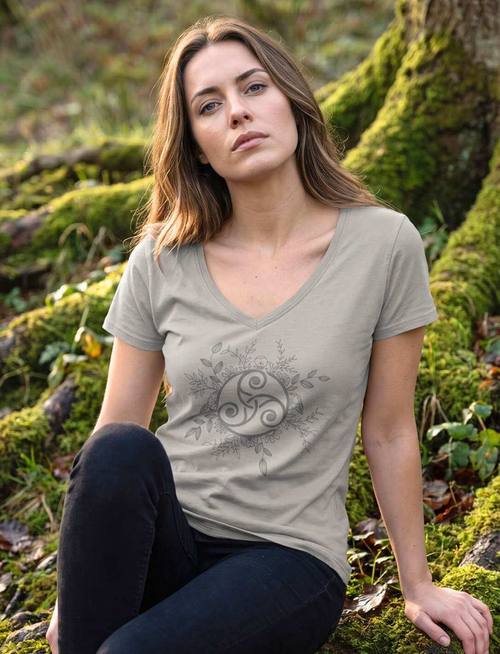Frau in hellgrauem V-Neck Shirt am Wurzelwerk sitzend, keltische Dreispirale in Nahaufnahme