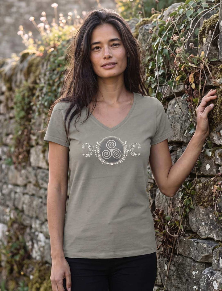 Frau in hellgrauem V-Neck Shirt vor einer bewachsenen Natursteinmauer im Abendlicht