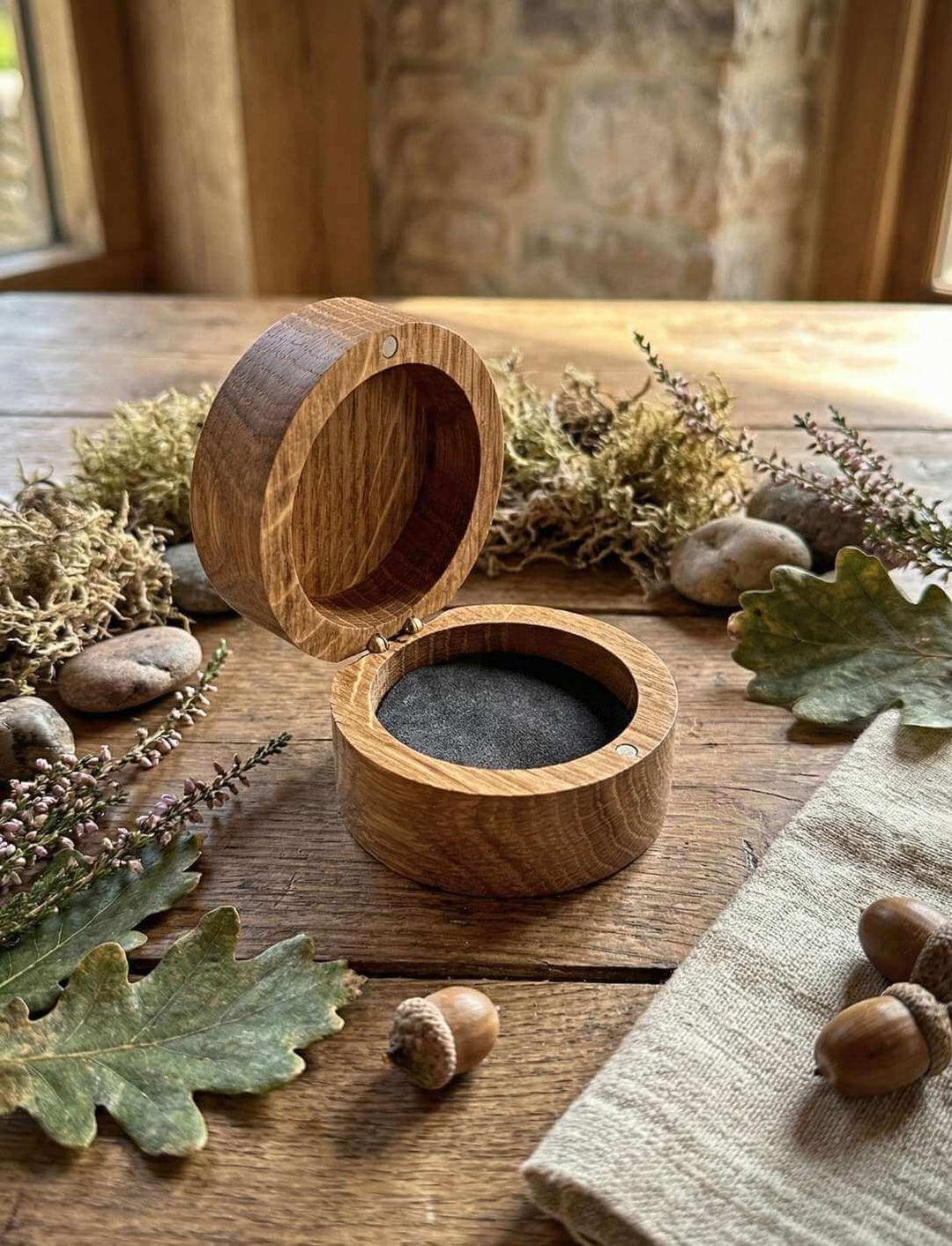 Geöffnete Triskele Schmuckdose mit Schaumstoff-Einlage auf Holztisch mit Eichenlaub und Moos