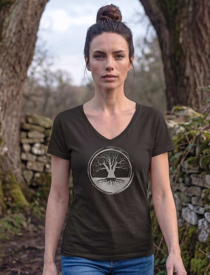 Frau in schwarzem V-Neck Shirt auf einem Waldweg neben moosbewachsener Mauer
