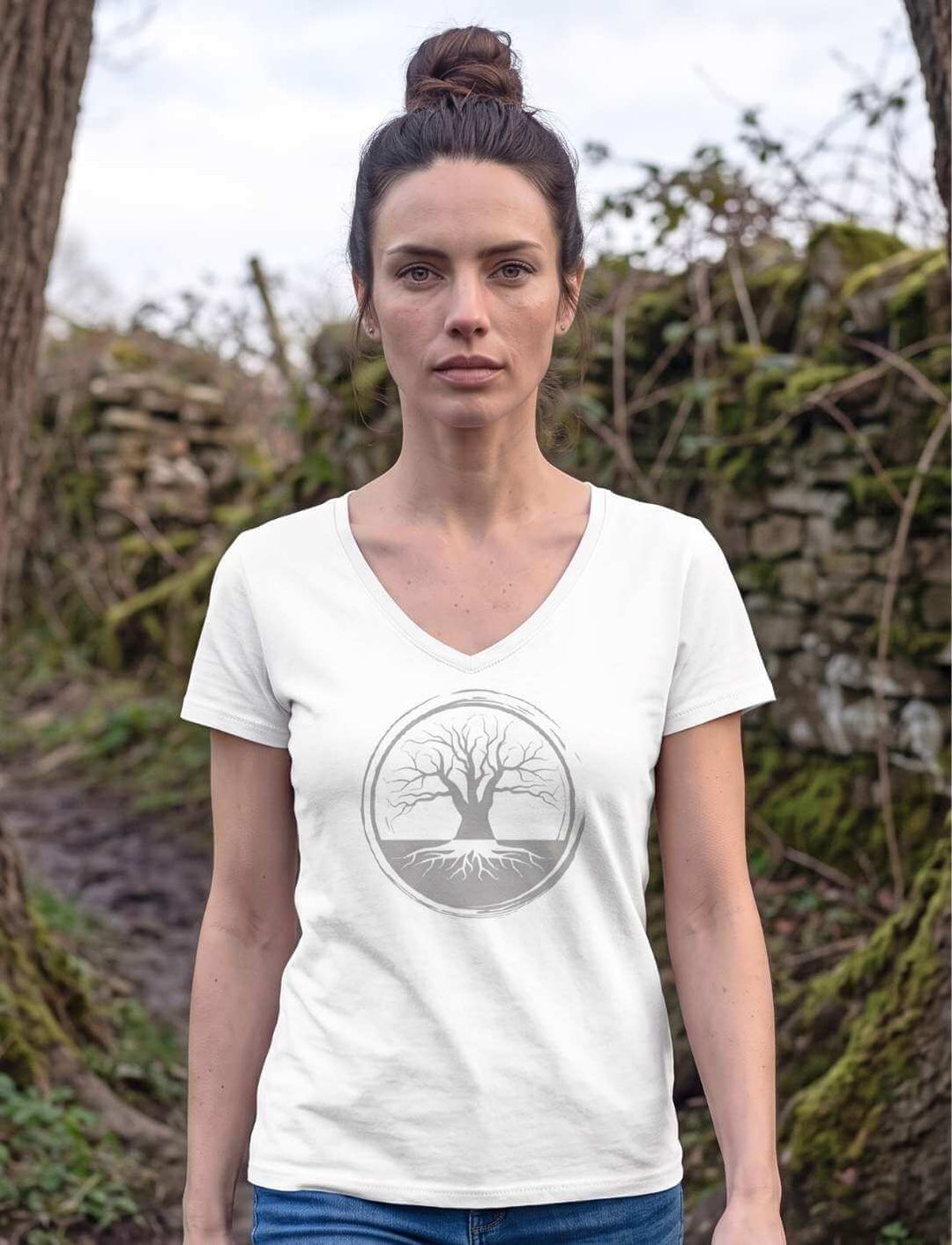 Frau in weissem V-Neck Shirt auf einem Waldpfad an einer alten Trockenmauer