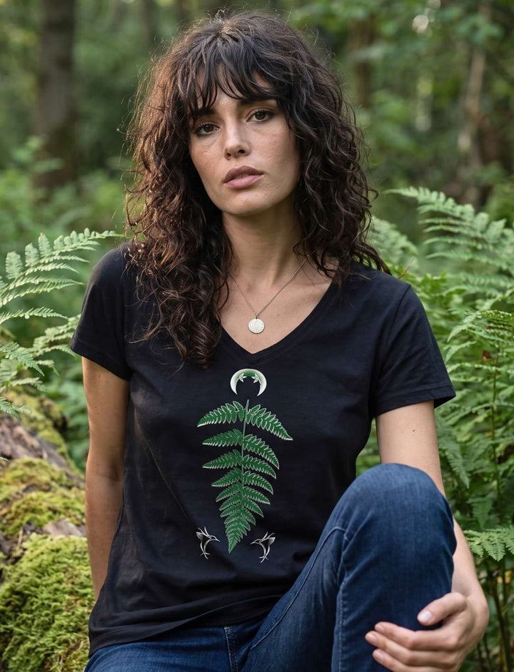 Frau sitzt auf einem bemoosten Stamm im Farn und traegt das Damen V-Neck Shirt Zauberhafte Naturwelt in Schwarz